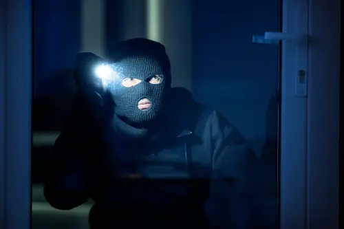 Einbrecher mit Maske und Taschenlampe