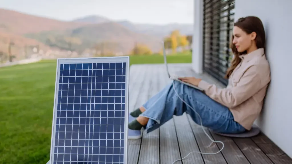 Frau lädt Laptop mit Solarpanel