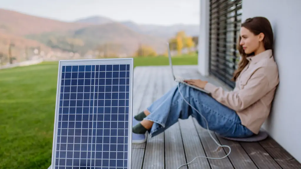 Frau lädt Laptop mit Solarpanel